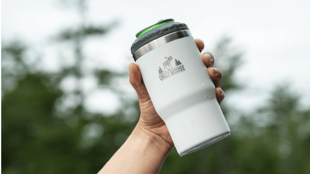 Chilly Moose premium reusable insulated tumblers and bottles. Pictured: New 40oz Summerhill Tumbler with handle and straw. Man's hand holding the tumbler by the handle in an outdoor forest path with autumn leaves on the ground.