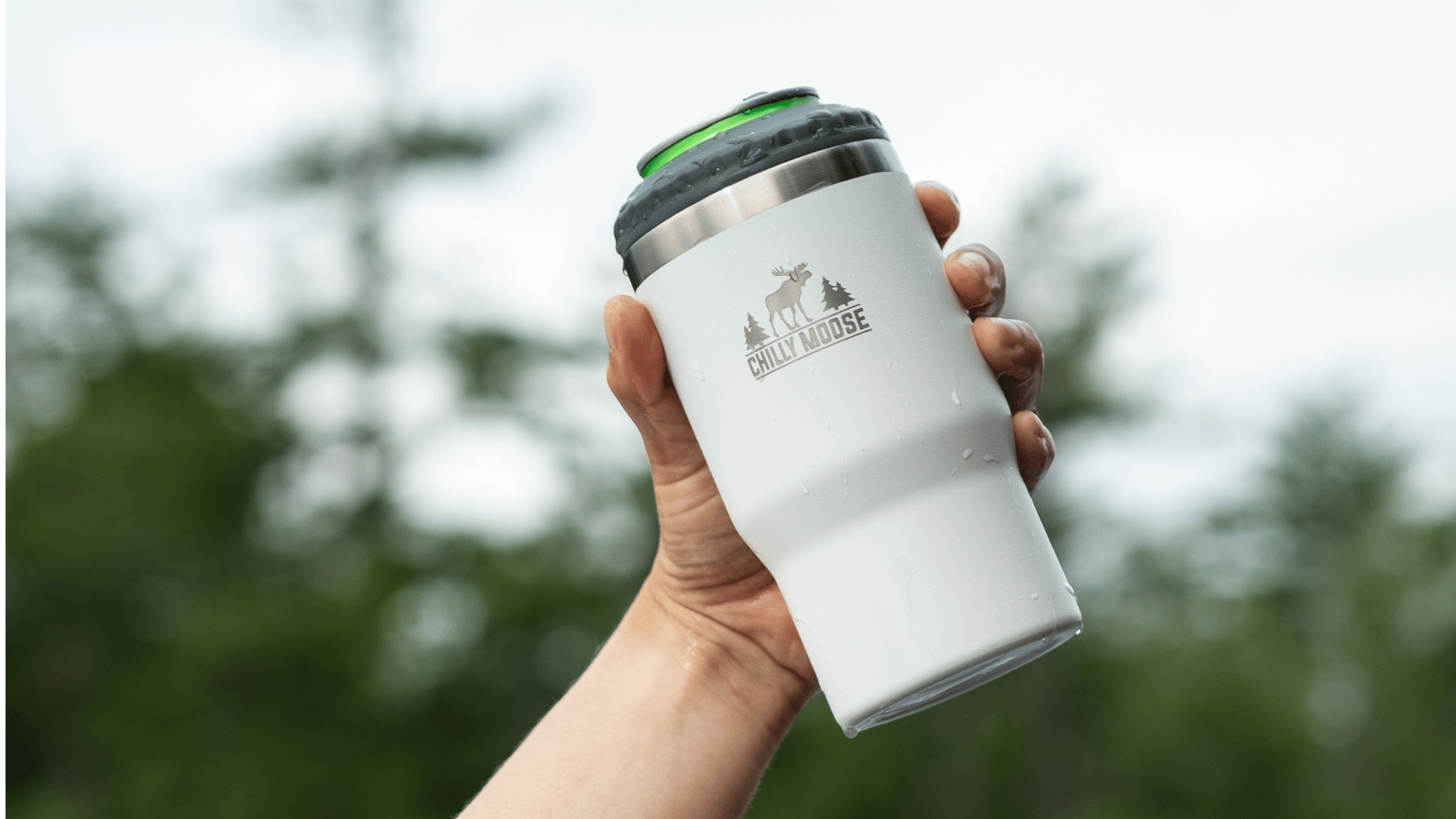 Chilly Moose premium reusable insulated tumblers and bottles. Pictured: New 40oz Summerhill Tumbler with handle and straw. Man's hand holding the tumbler by the handle in an outdoor forest path with autumn leaves on the ground.