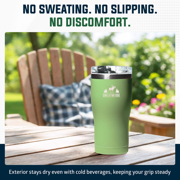 A mint green insulated tumbler with a clear lid and a white 'CHILLY MOORE' logo on the front, set on a wooden outdoor table with a blurred garden chair and greenery in the background. Text at the top reads 'NO SWEATING.#colour_sage