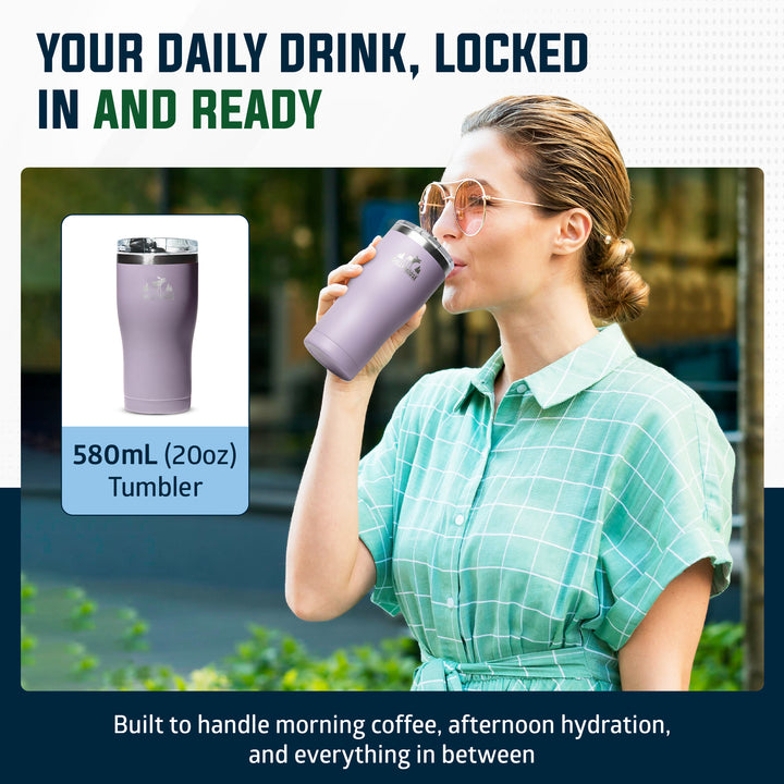A woman in a mint green plaid shirt drinks from a lavender purple 580mL (20oz) tumbler. The image includes a product inset showing the tumbler alone on a white background, with promotional text reading 'YOUR DAILY DRINK, LOCKED IN AND READY' and 'Built to handle morning coffee, afternoon hydration, and everything in between.#colour_thistle