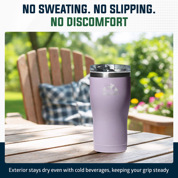 A lavender insulated tumbler with a clear lid sits on a wooden outdoor table, with a blurred Adirondack chair and green garden in the background. Text at the top reads 'NO SWEATING.#colour_thistle