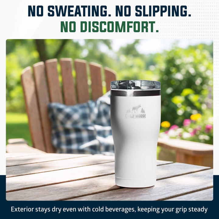 A white insulated tumbler with a clear lid sits on a wooden outdoor table, with a blurred garden chair and greenery in the background. Text at the top reads 'NO SWEATING.#colour_frost-white