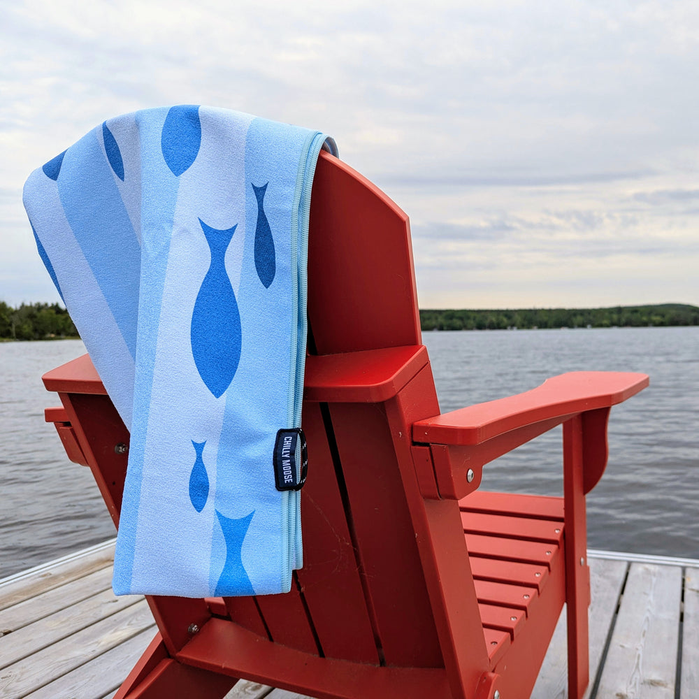 Sandbanks Quick Dry Travel Towel – Chilly Moose – Draped on red chair by lake #style_current-club-quick-dry-travel-towel