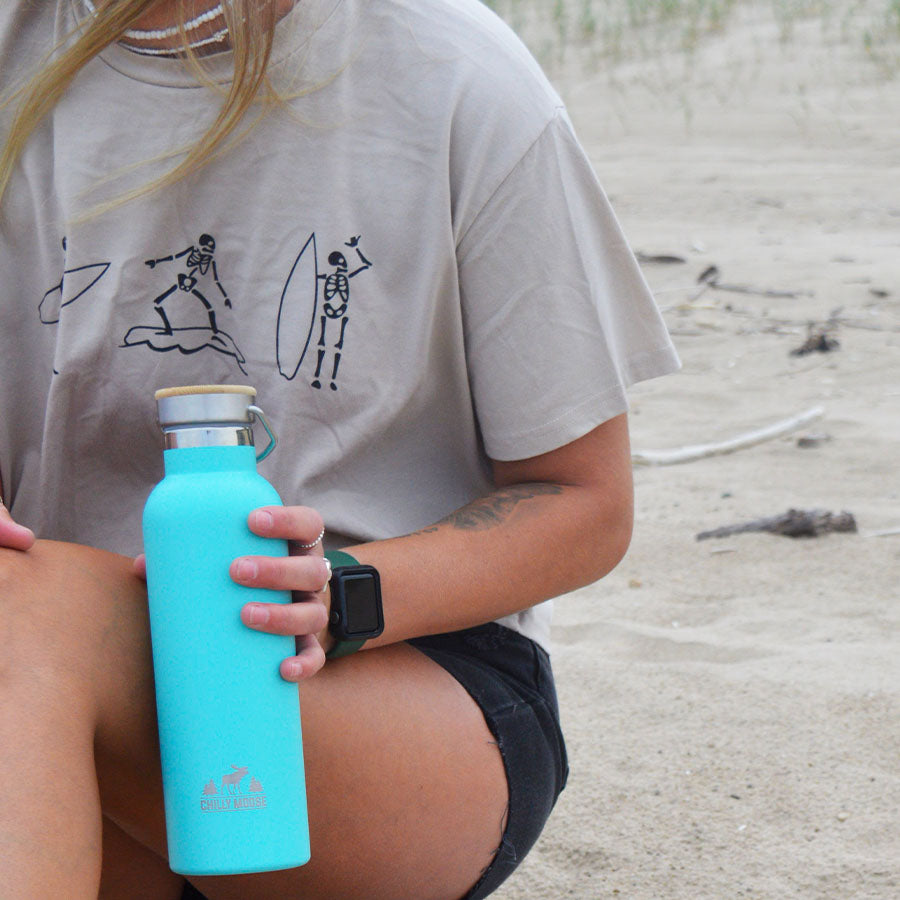 25oz Whitney Bottle in Southampton – Chilly Moose – Lifestyle shot on beach held by person in gray tee #colour_southampton