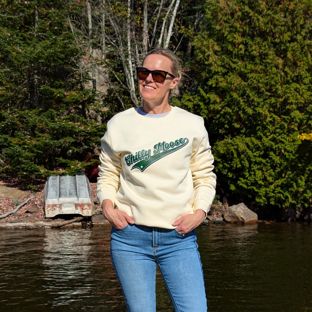 Varsity Crewneck in Cream – Chilly Moose – Woman by lake wearing cream sweatshirt, lifestyle shot #colour_cream